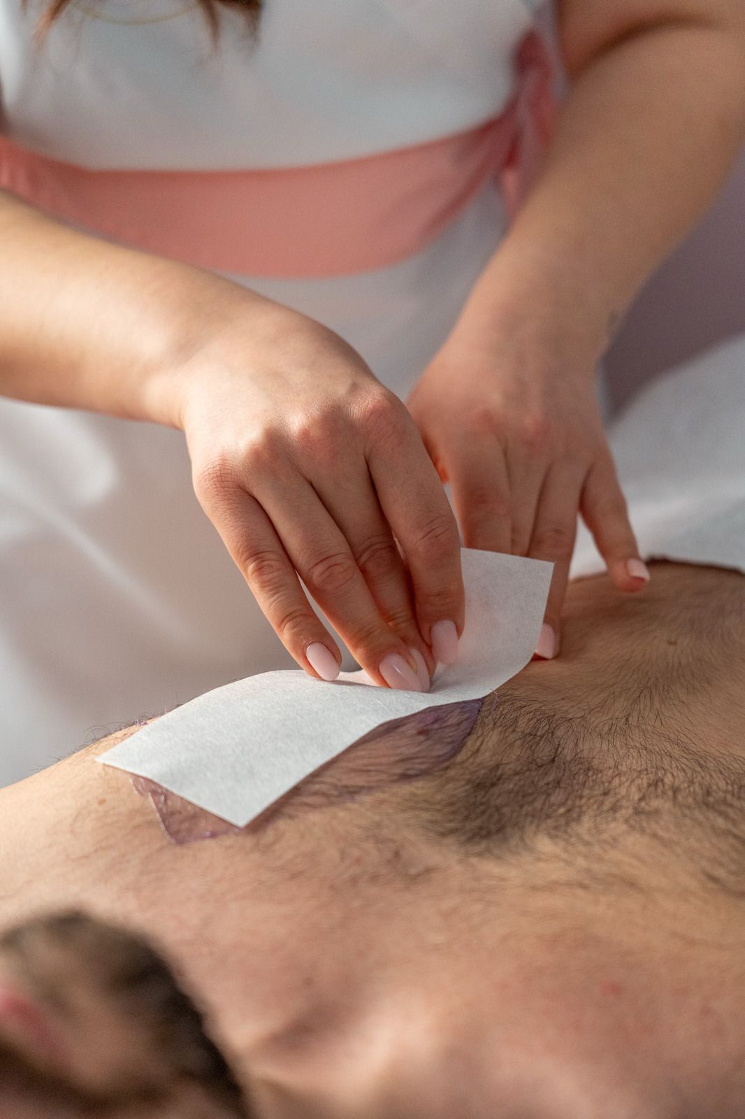 Una donna sta depilando il petto di un uomo in un salone di bellezza.