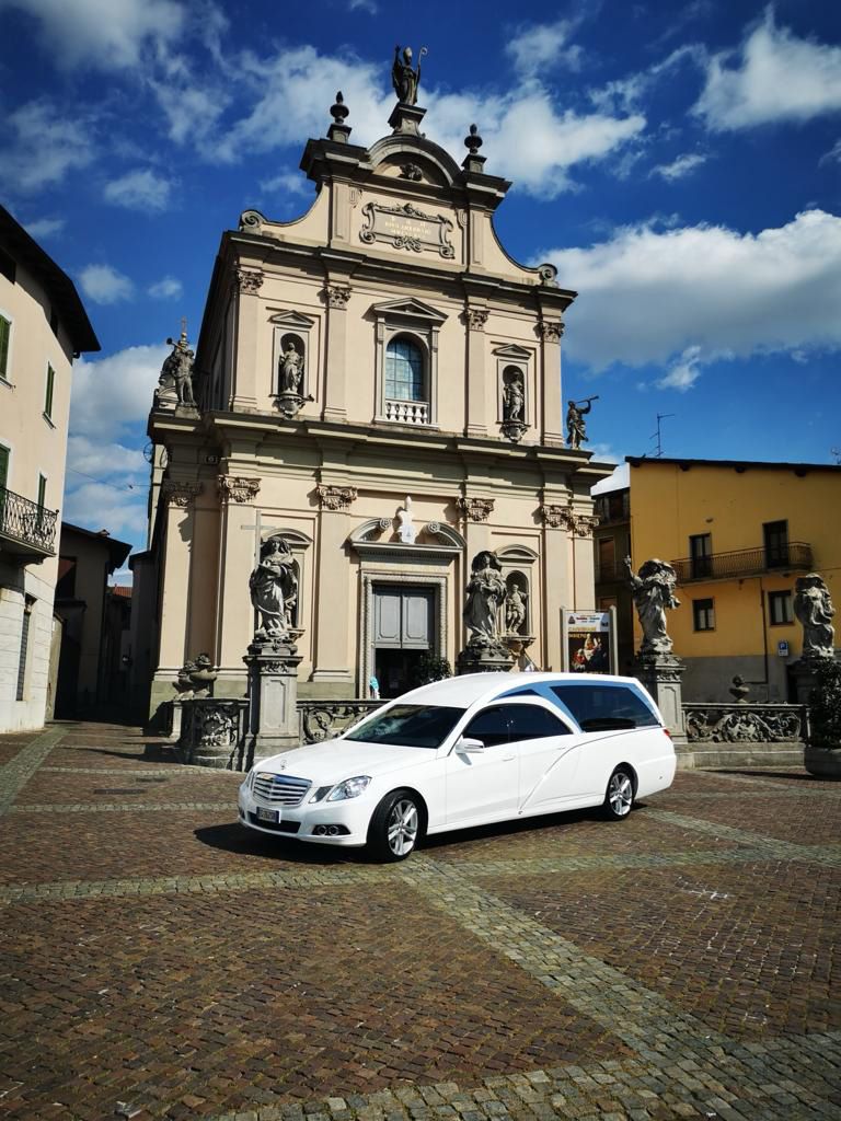 un carro funebre bianco è parcheggiata davanti a una chiesa.