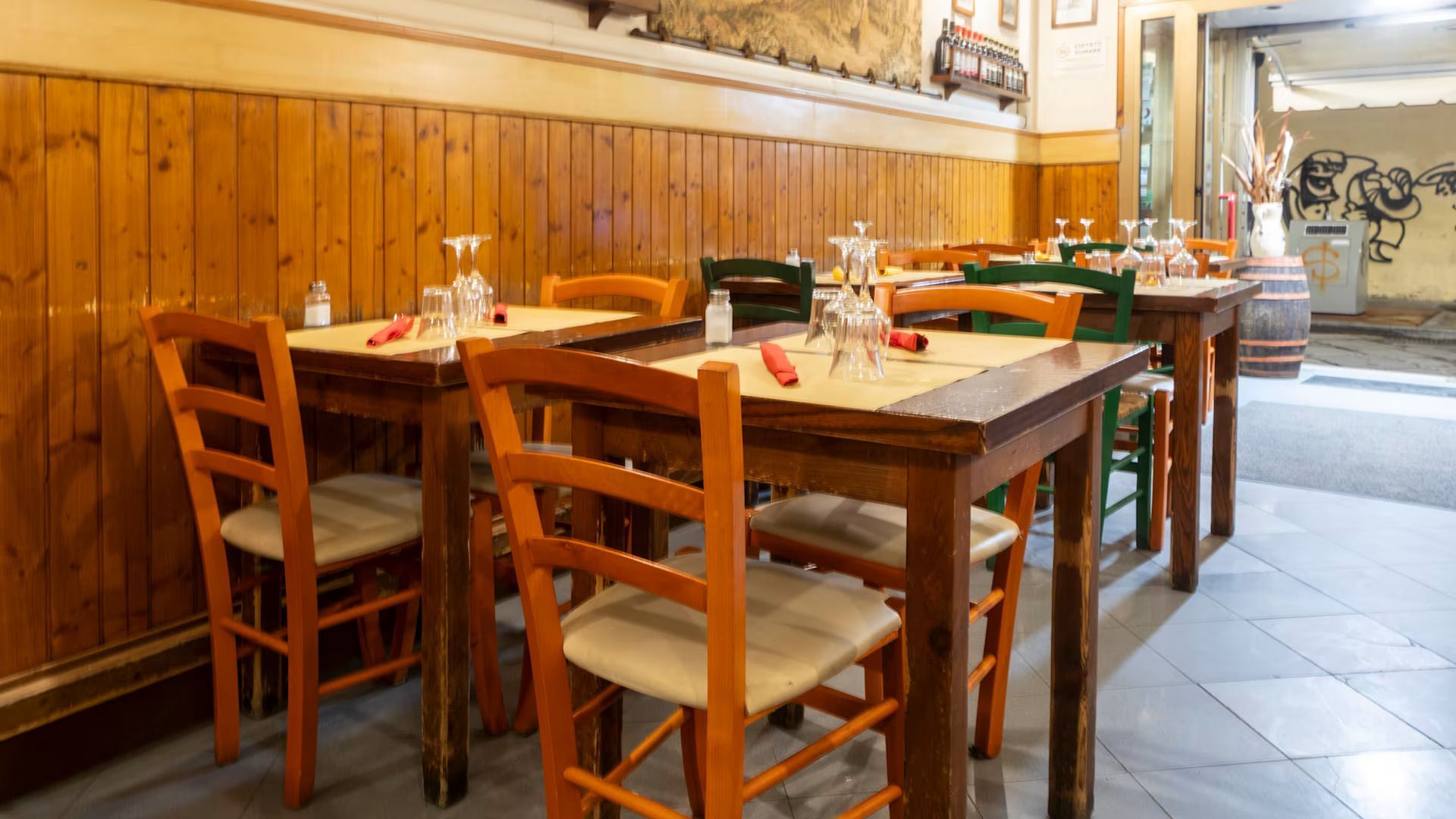 Accogliente interno del ristorante con tavoli e sedie in legno e calde pareti rivestite in legno.