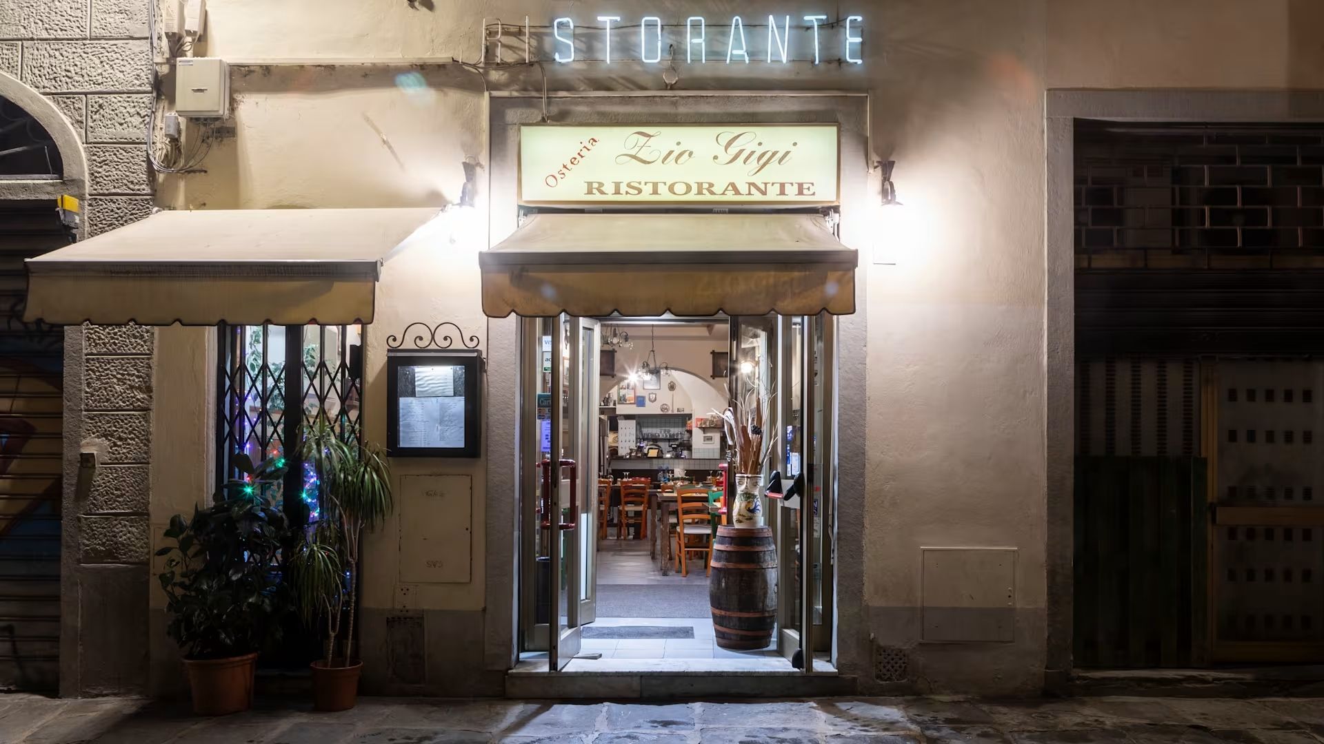 Facciata illuminata di un ristorante di notte, con porte aperte e calda illuminazione interna.