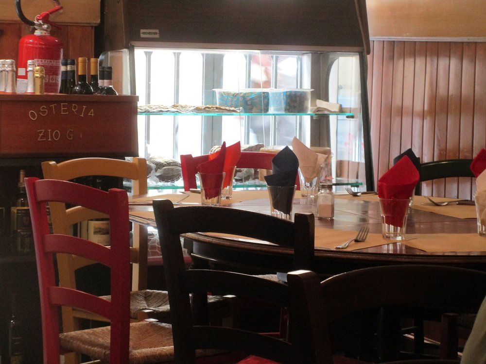 Tavoli da ristorante con tovaglioli rossi accanto a un acquario e sedie di legno in un'accogliente sala da pranzo.