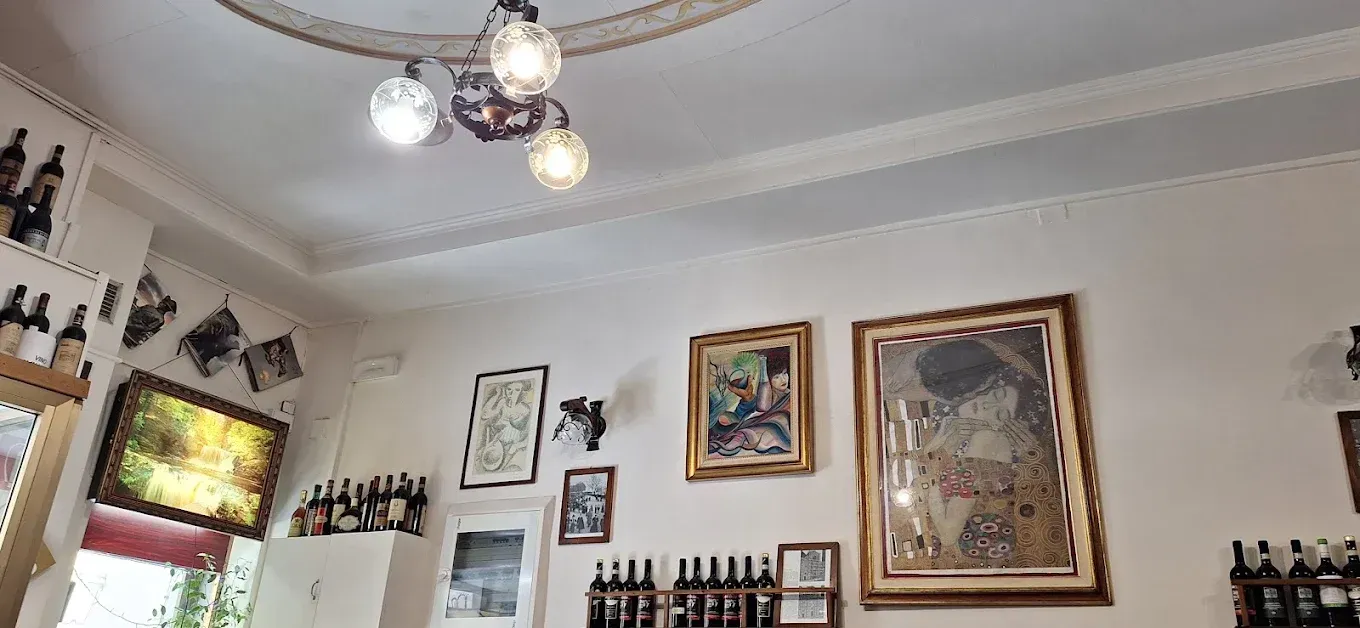 Camera accogliente con opere d'arte alle pareti, quadri incorniciati e una lampada a sospensione.
