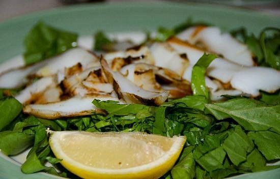 Insalata verde condita con pollo grigliato a fette e uno spicchio di limone.