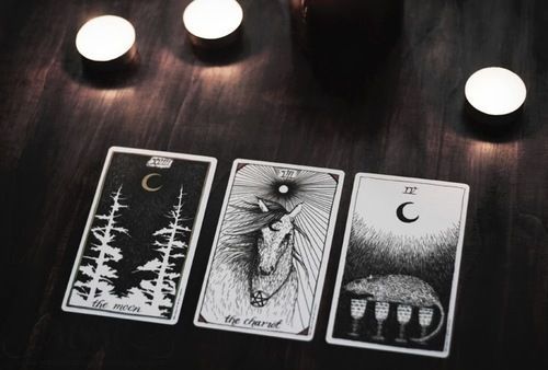 Three tarot cards on a wooden surface