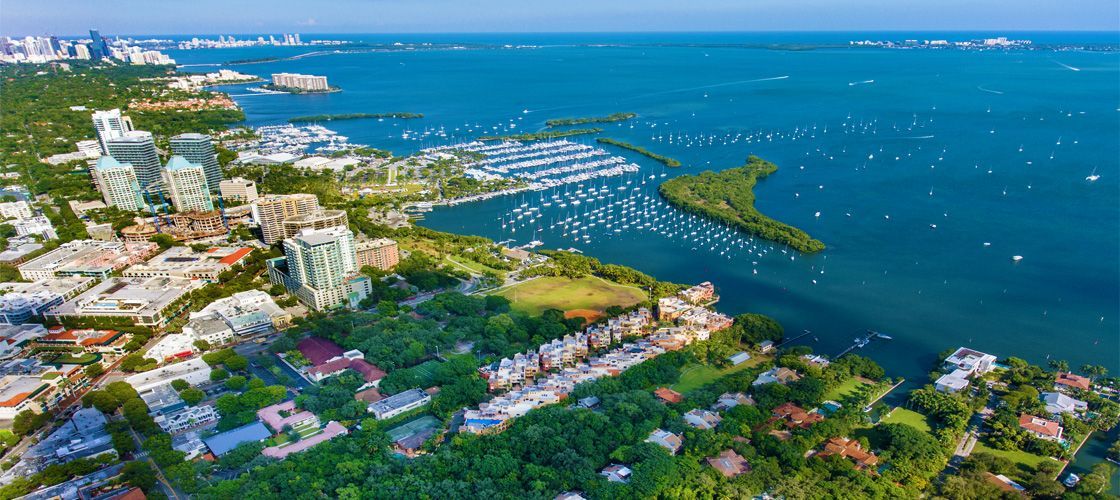 Aerial view of a coastal city with boats in the water and green vegetation.