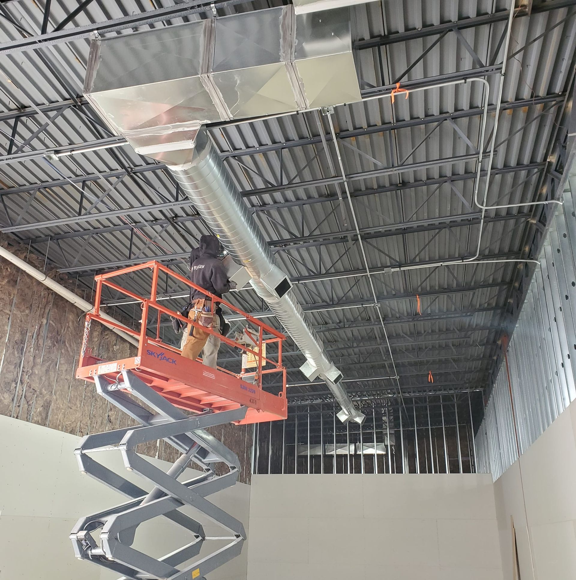 A man is standing on a scissor lift working on a ceiling.