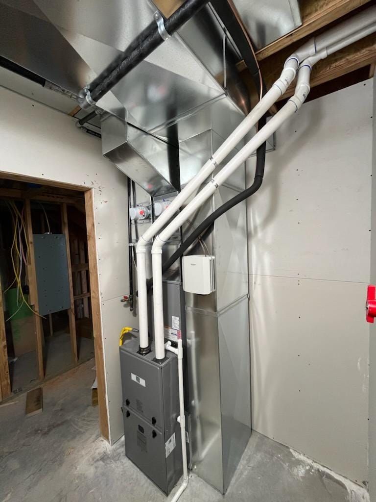 A room with a furnace and pipes hanging from the ceiling.