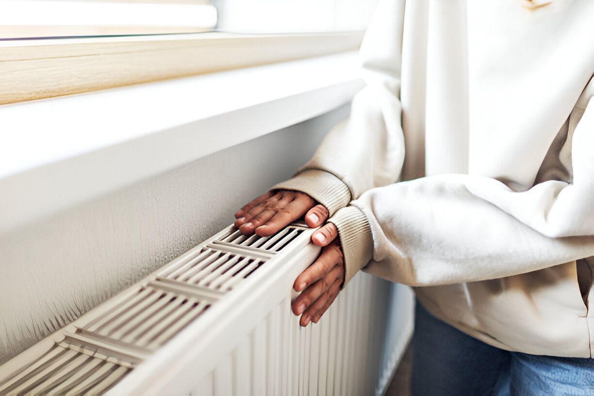 A person is touching a radiator with their hands.