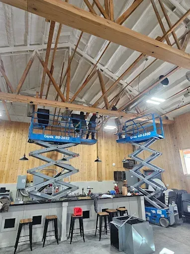 Two scissor lifts are being used to work on the ceiling of a building.