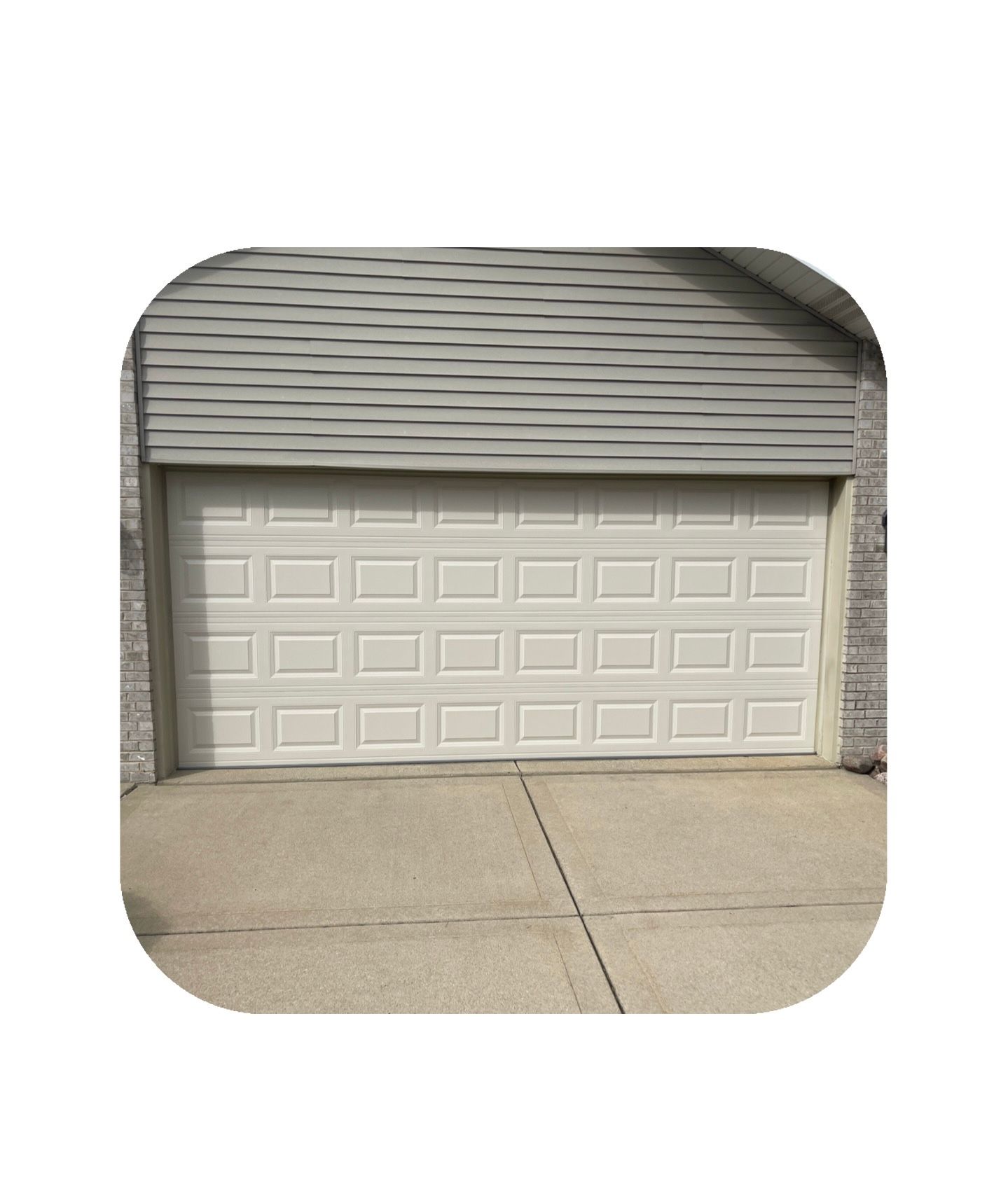 White garage door on a house with gray siding. Concrete driveway in front.