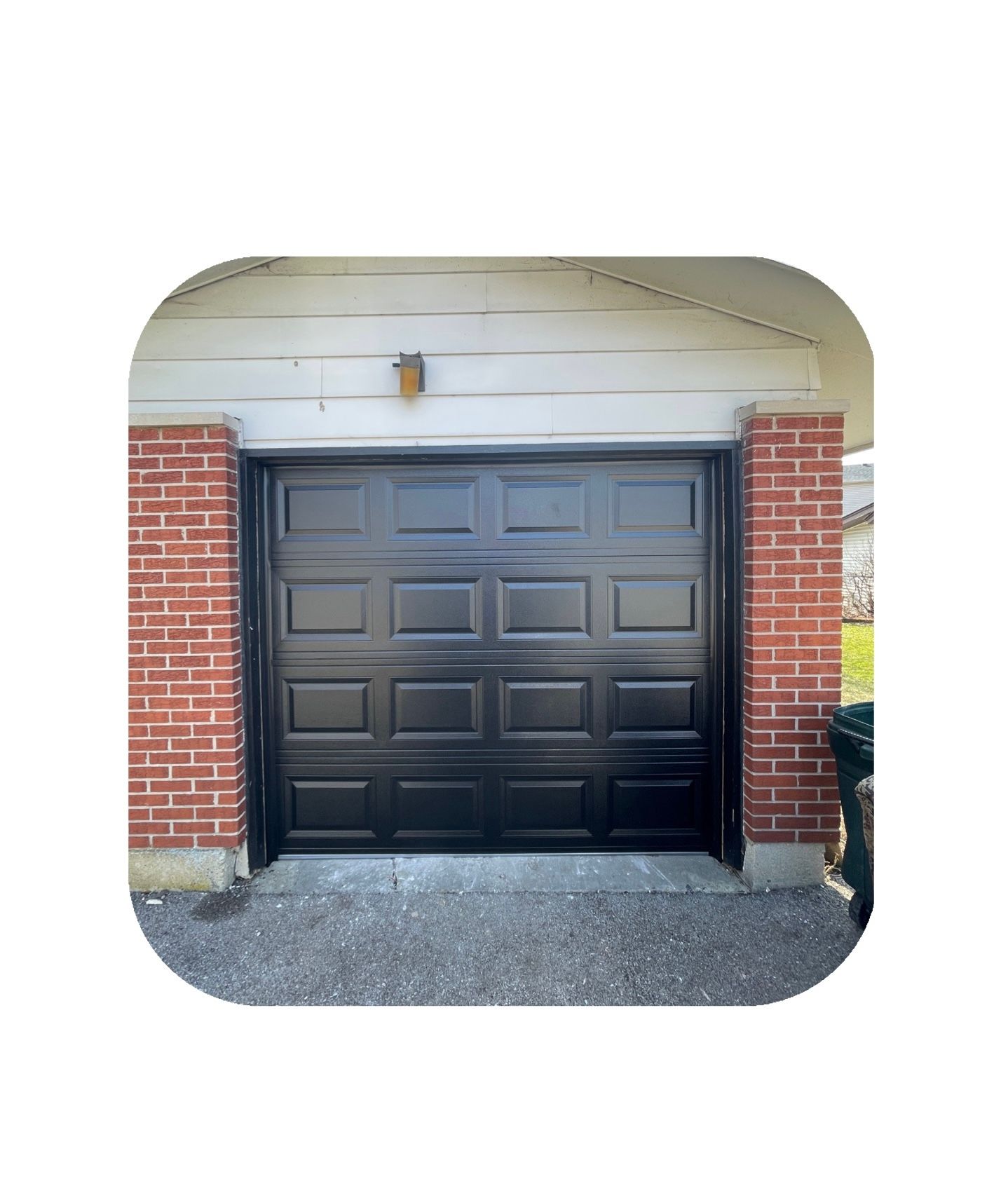 Black garage door framed by red brick pillars.