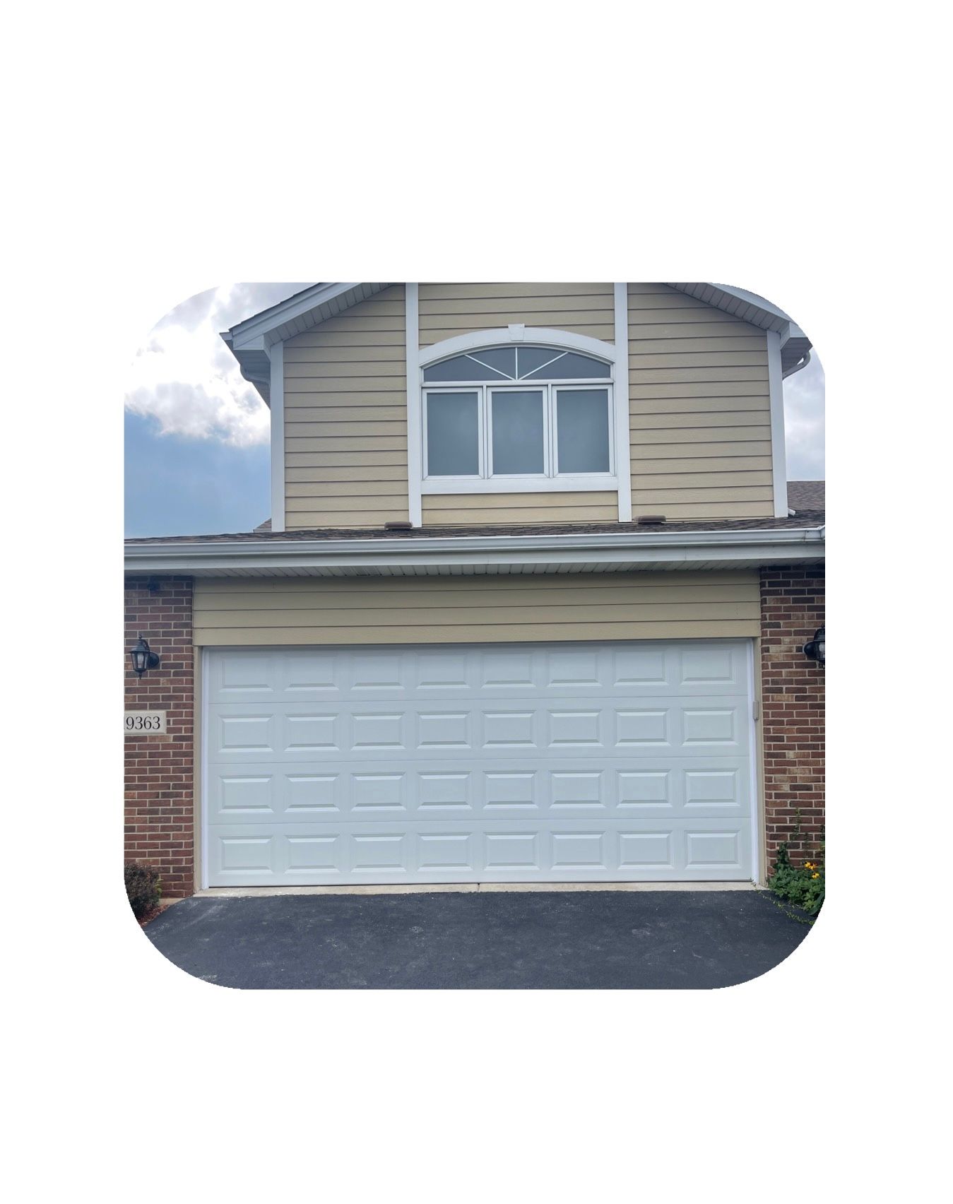 White garage door on a beige house with a window above.