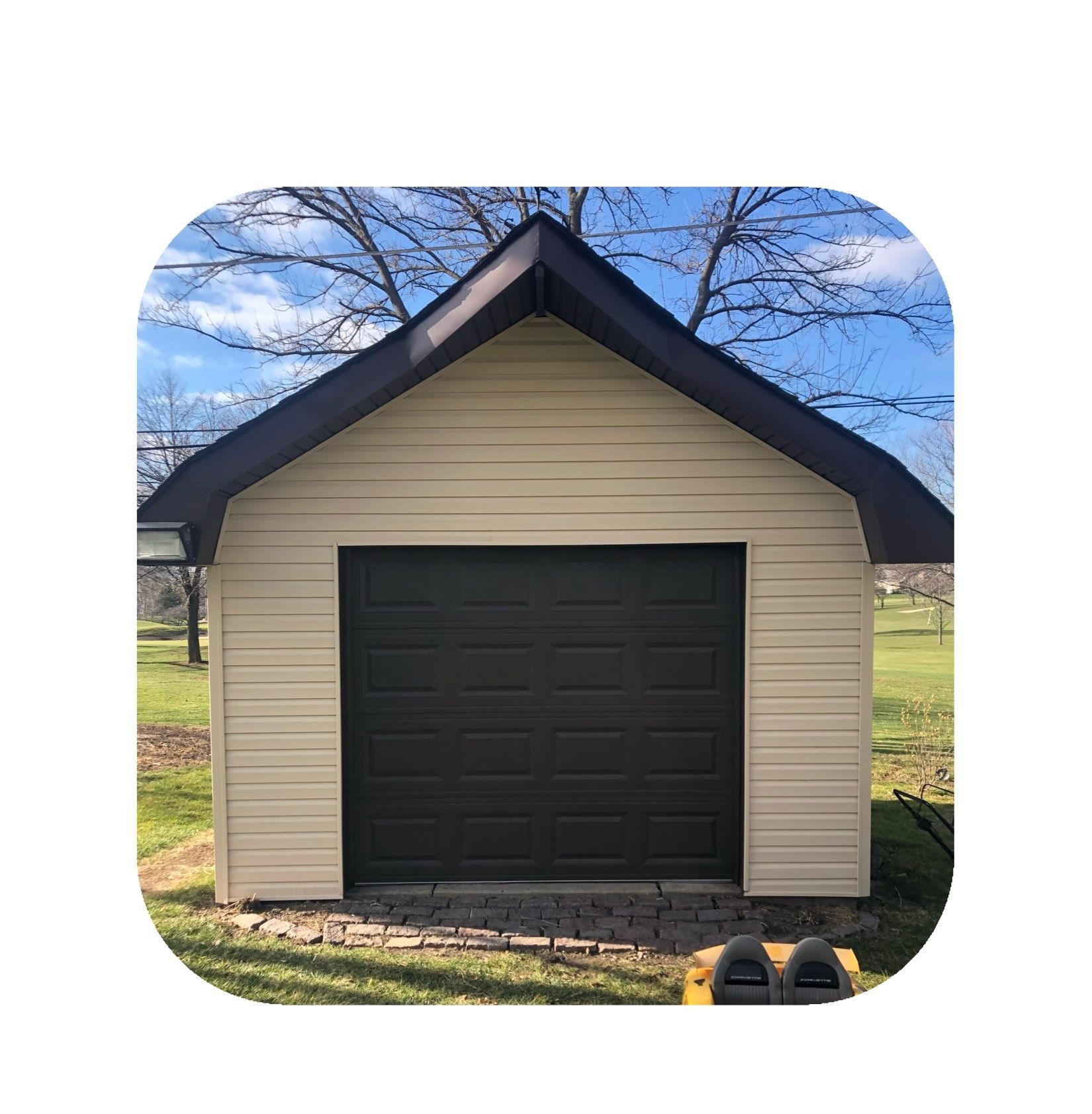 Tan and brown garage with a dark door, beneath a blue sky.