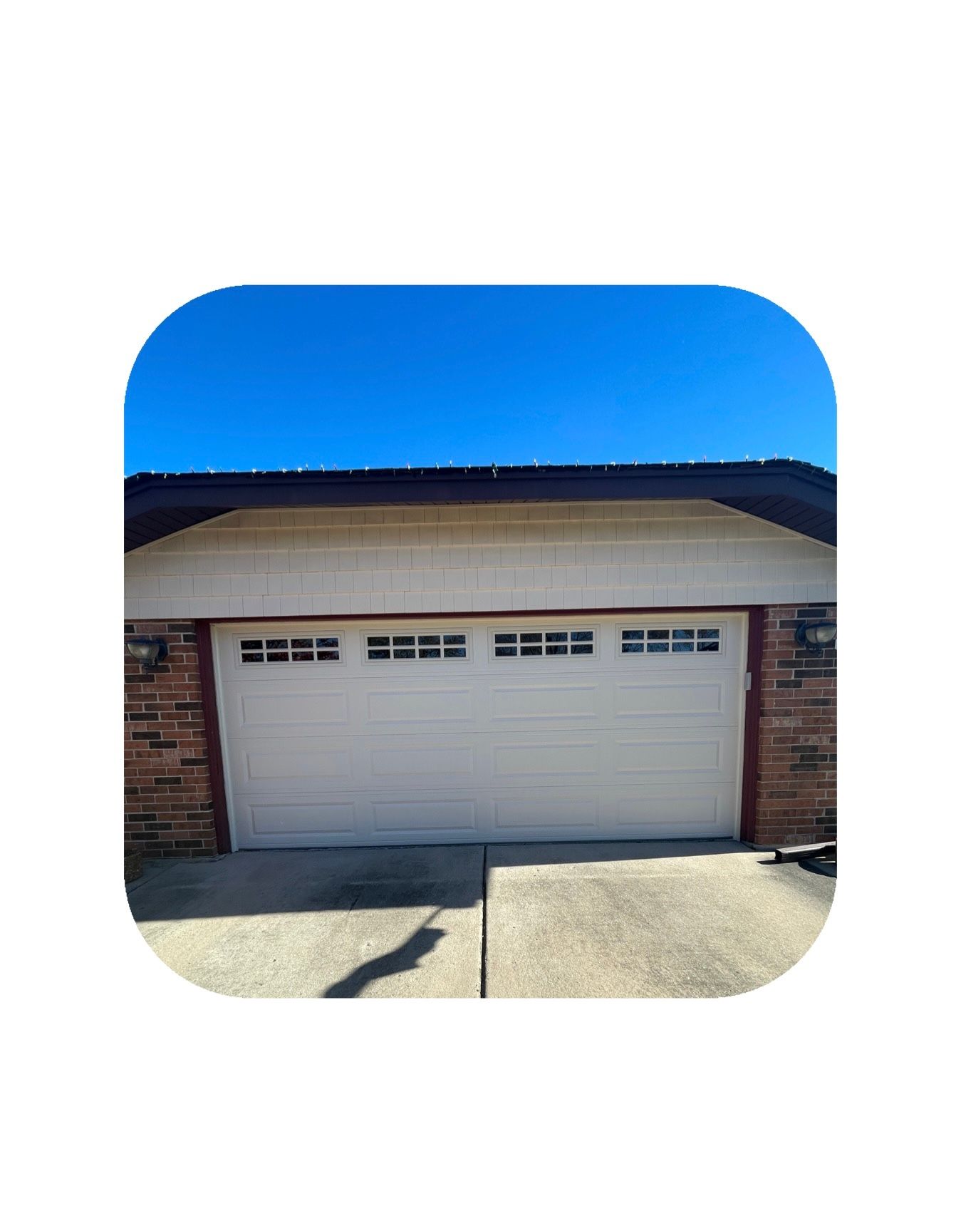 White garage door with windows, brick accents, under a clear blue sky.