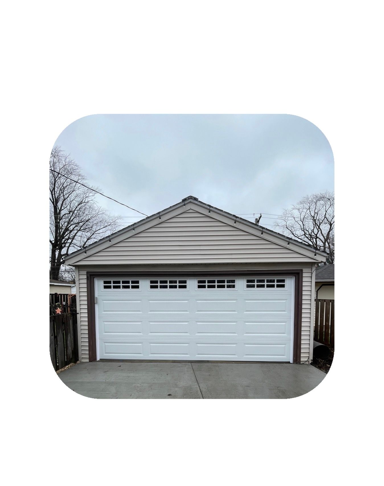White garage with a light brown roof and siding, under a cloudy sky.