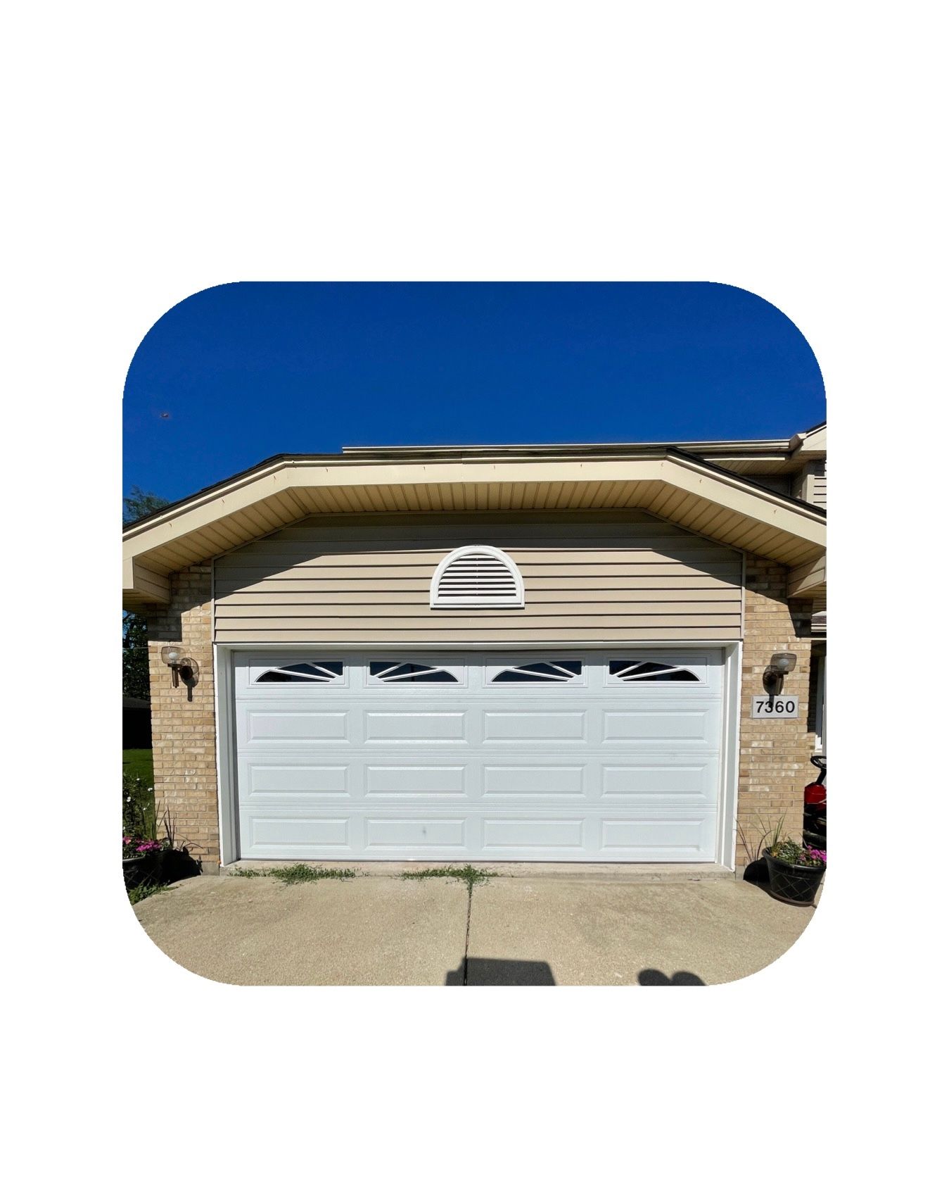 White garage door under a beige house with a blue sky background.