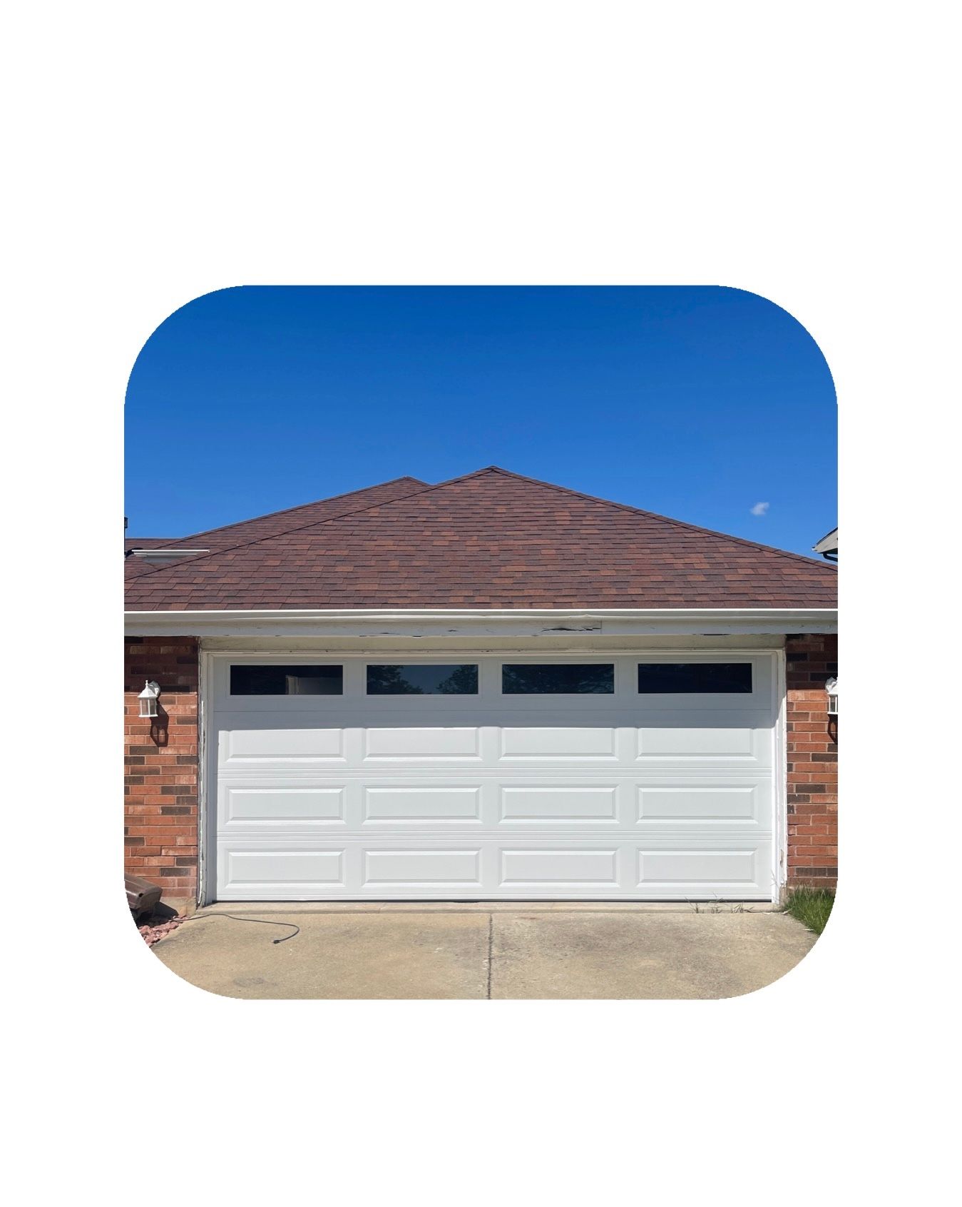 White garage door with brown roof against a blue sky.