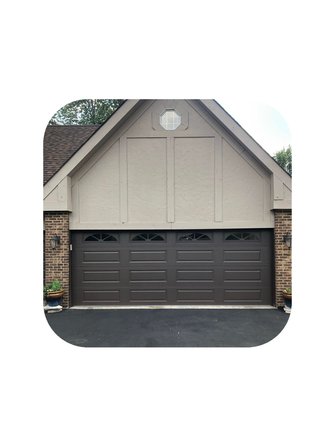 Brown garage door on a house with a tan exterior and a dark roof.