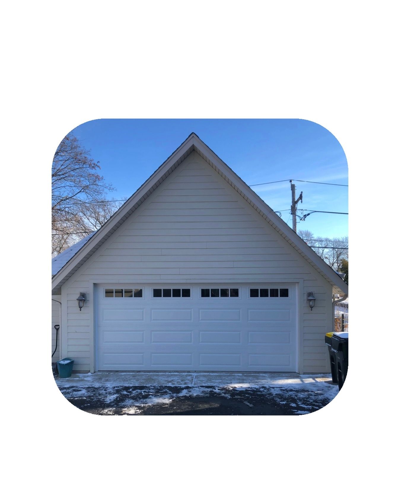 White garage with a light-colored roof, a white garage door, and some snow on the ground.