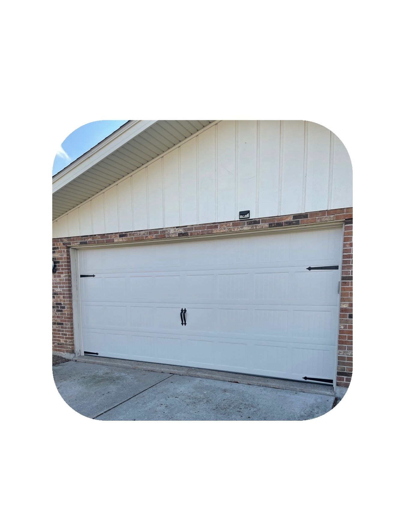 White garage door with black hardware, brick facade.