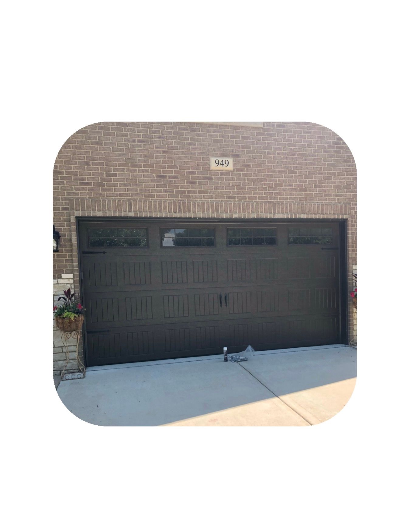 Brown garage door with windows, in front of a brick wall. Number plaque above.