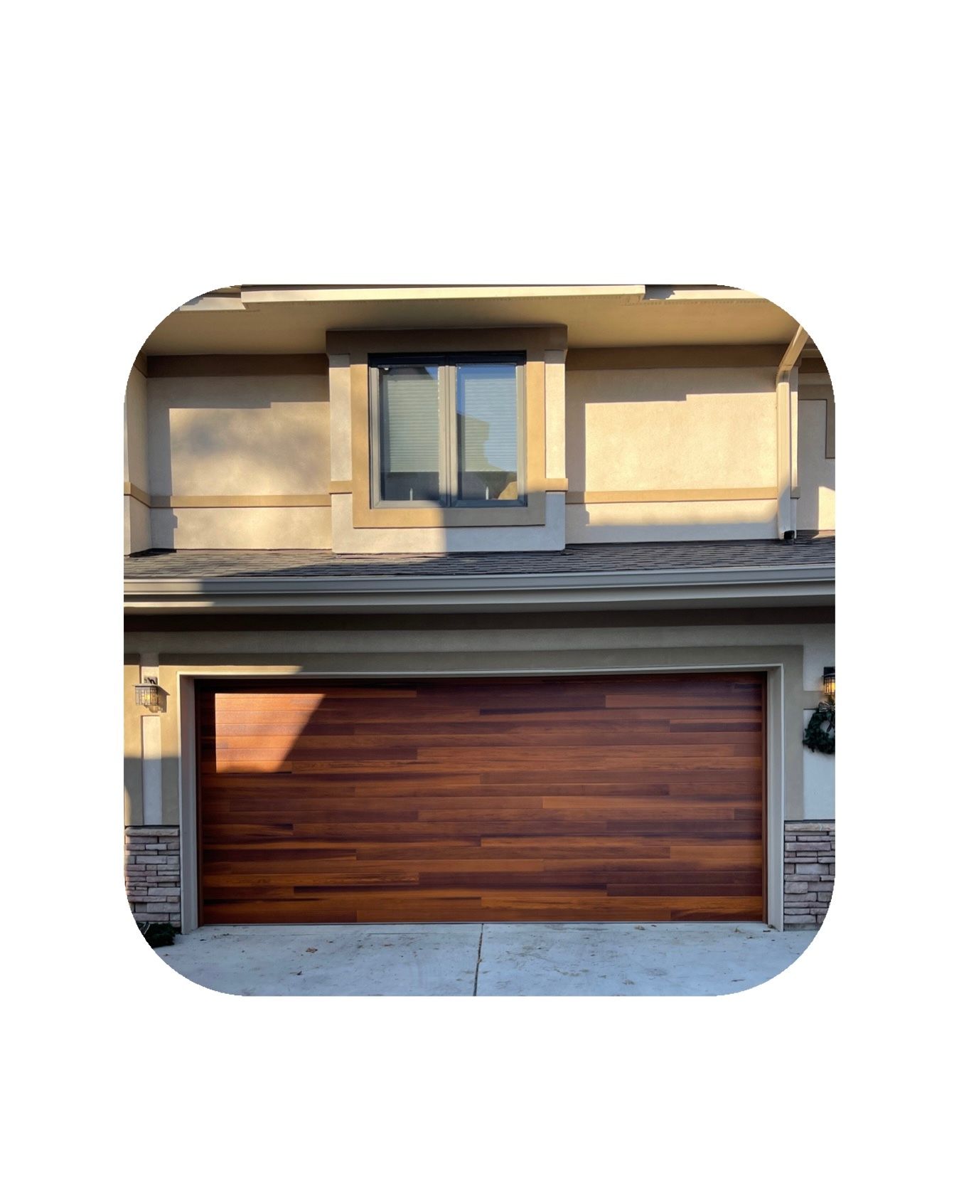 Brown wooden garage door on a beige house with a small window above.