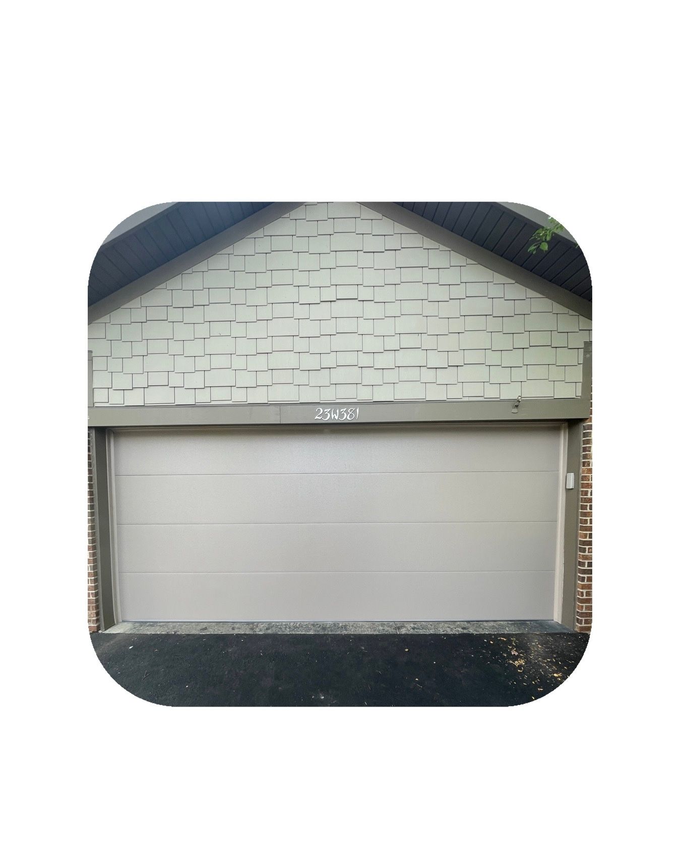 Tan garage door under a light green brick facade.