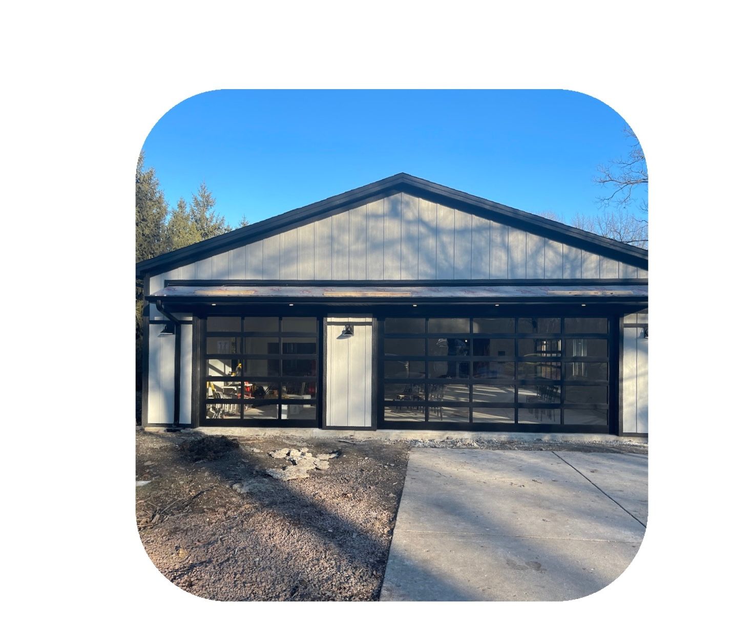Two-car garage with glass doors and a black-framed roof against a blue sky.