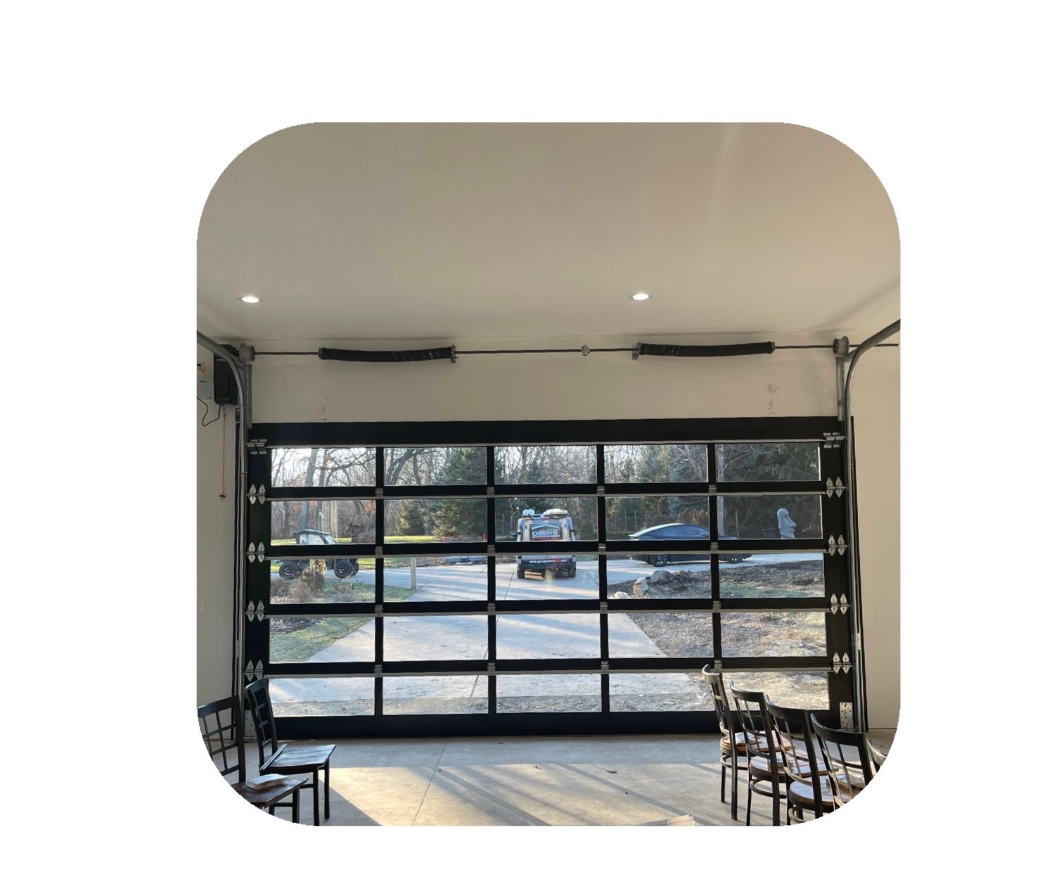 Glass garage door open to exterior, with chairs inside.