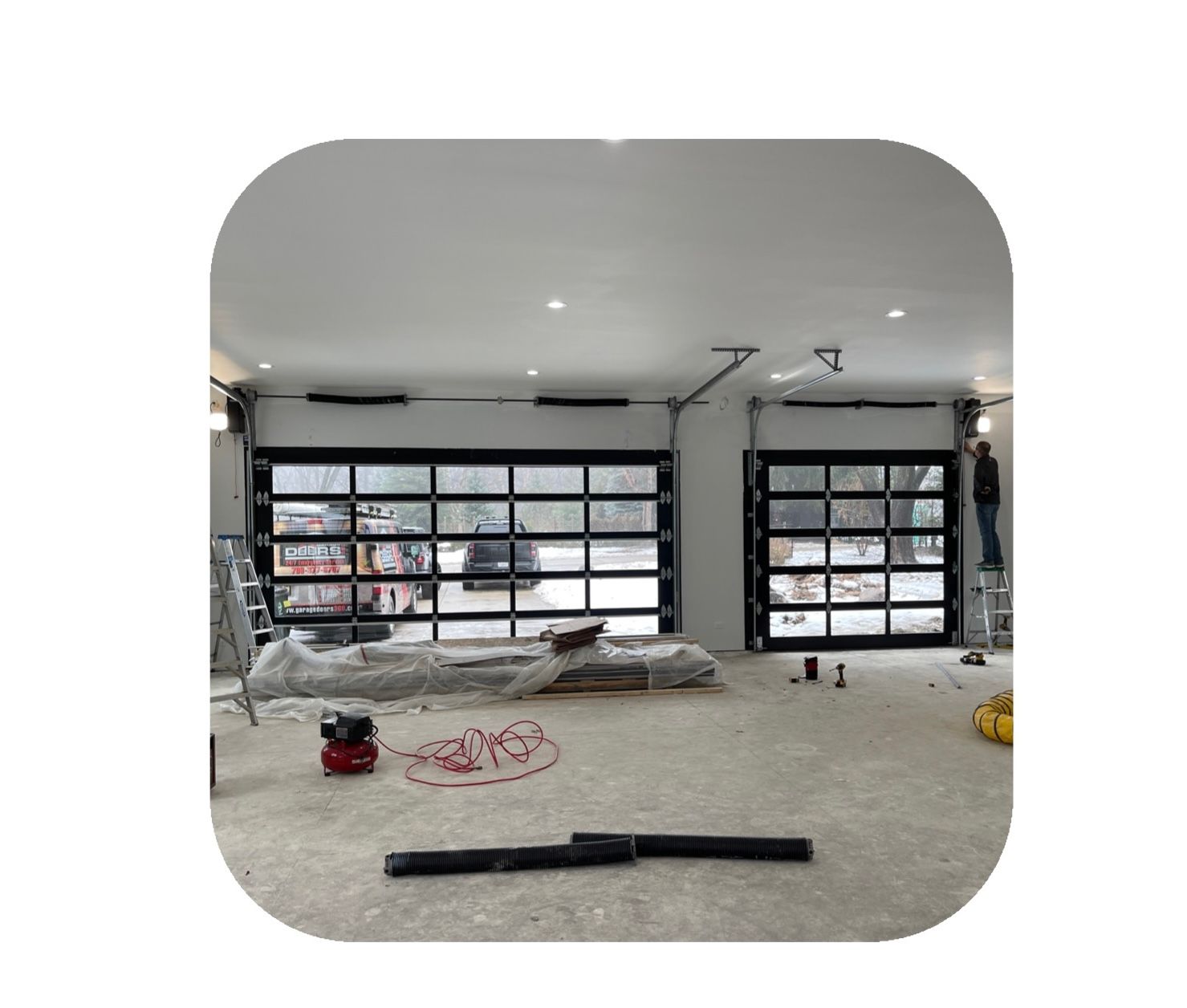 Two glass garage doors being installed in a light-filled interior.