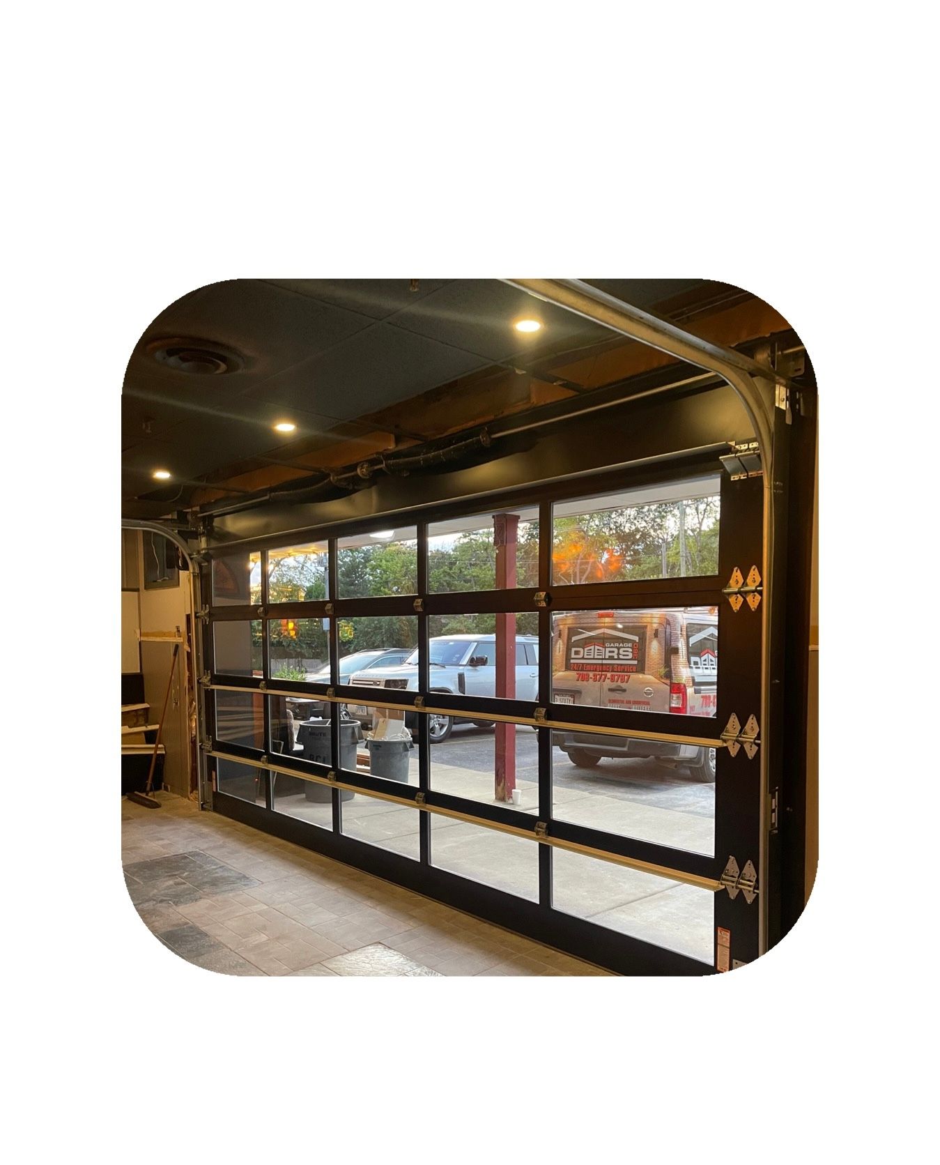 Glass garage door open, revealing outdoor scene with parked vehicles and red pole.