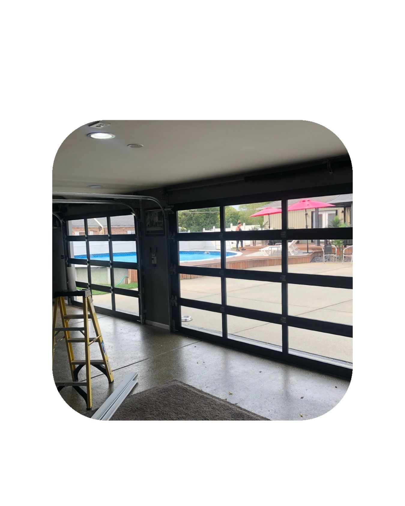 Glass garage door opens to a pool and patio. A ladder and interior visible.