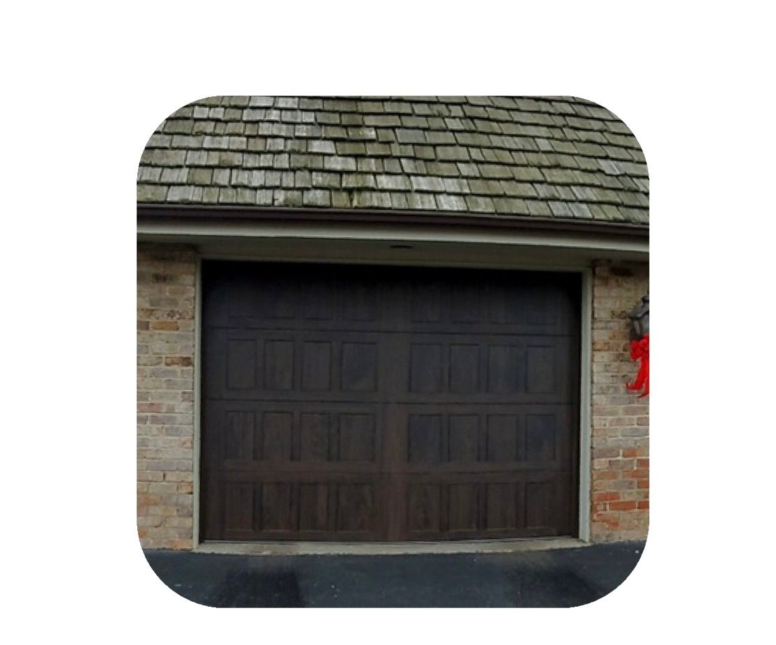 Dark brown garage door, brick facade, and weathered shingle roof.