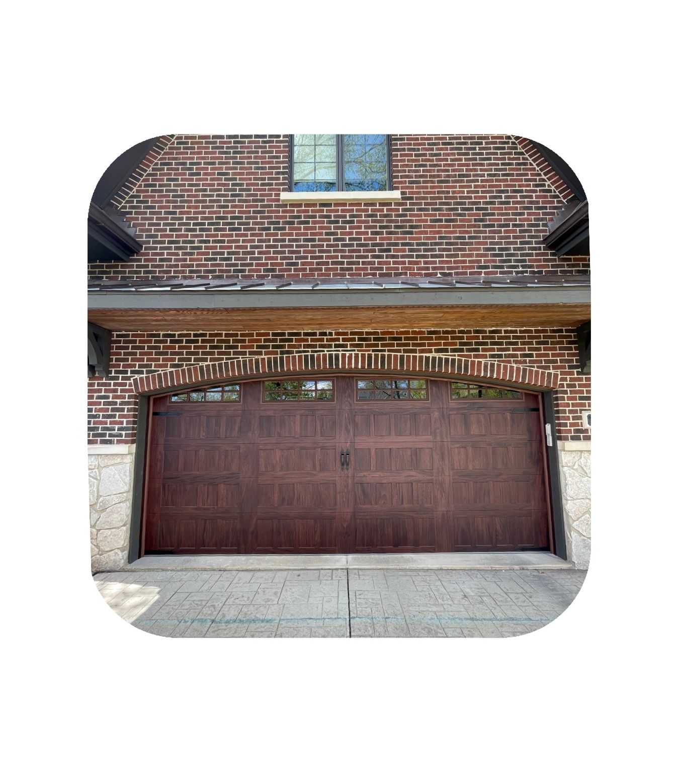 Brick house with a brown garage door under an arched doorway.
