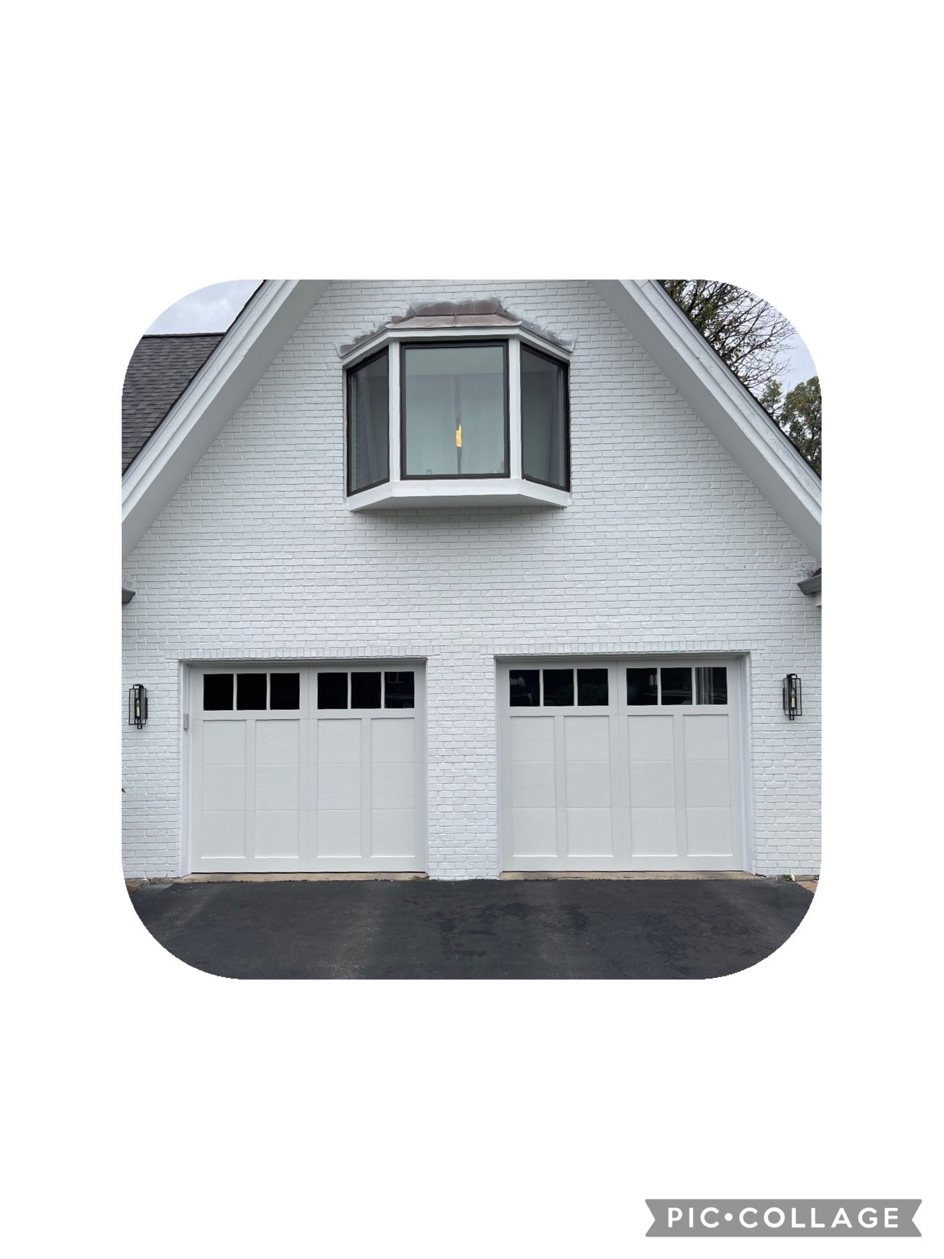 White house with a two-car garage, white garage doors and a bay window.