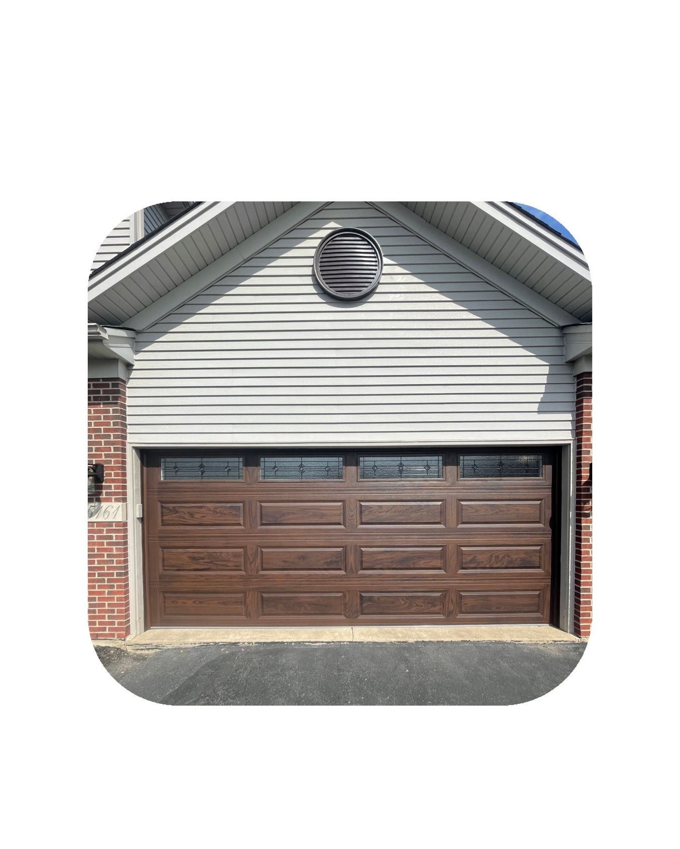 Brown garage door with windows, on a house with gray siding and brick.