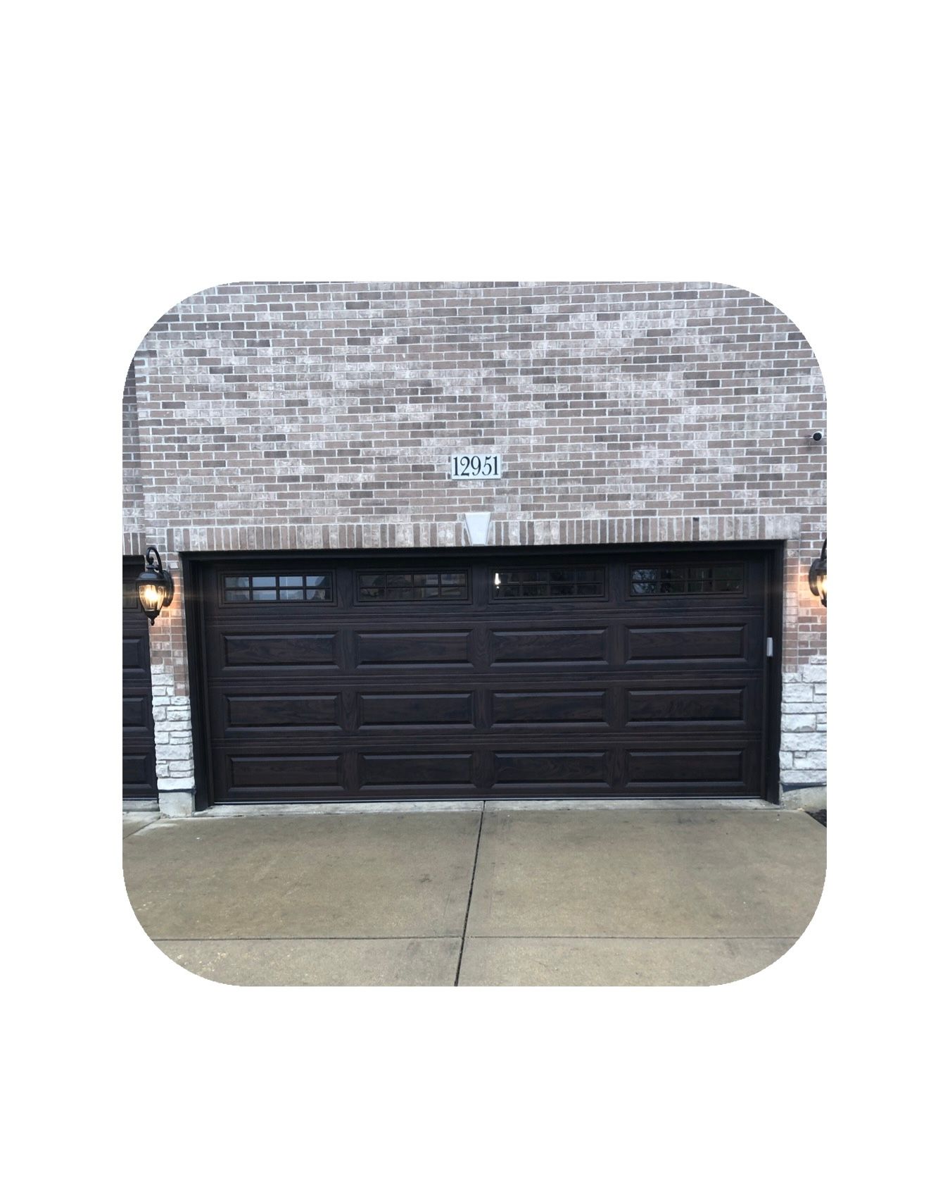 Brown garage door with windows, in front of a brick building.