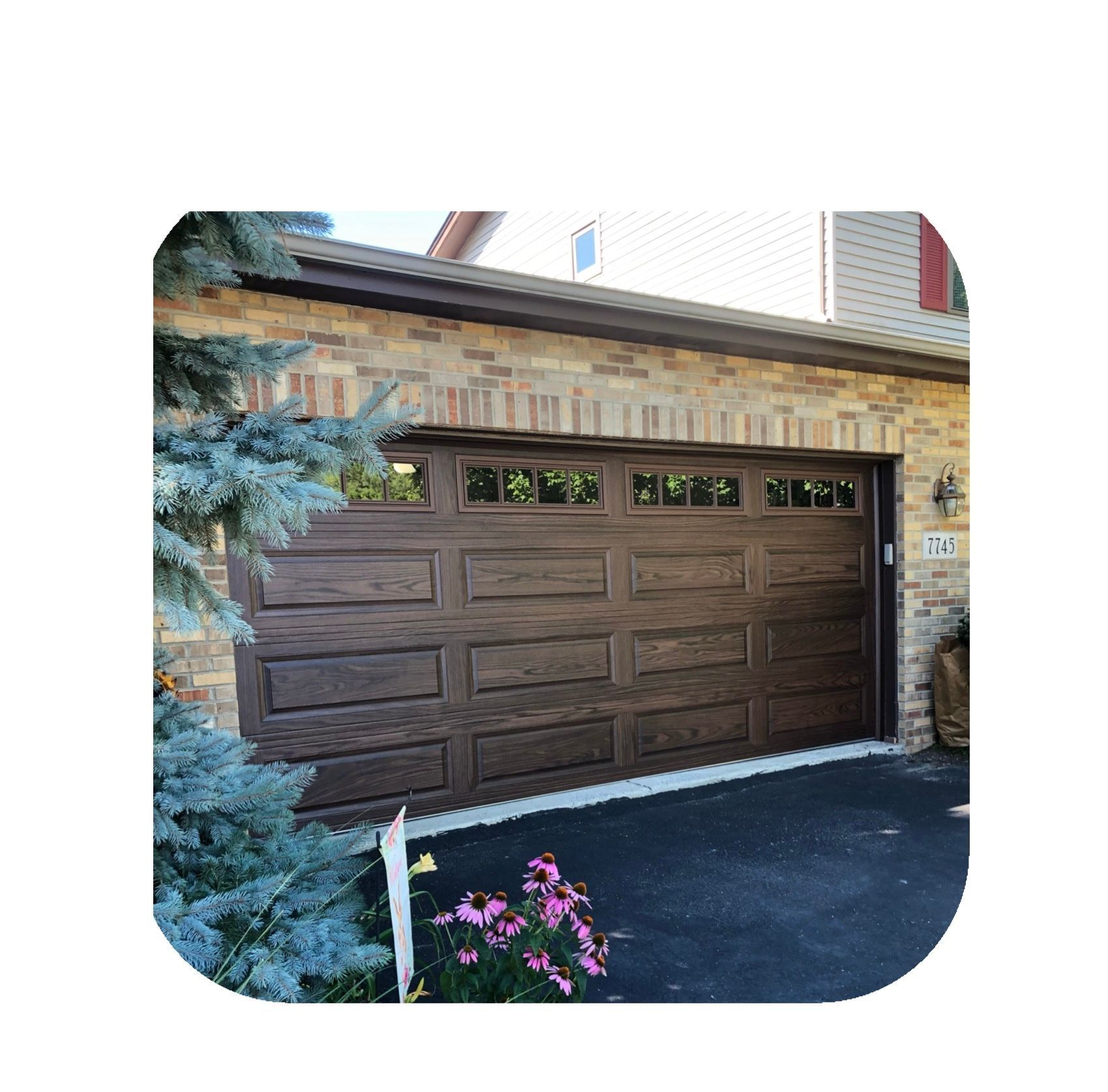 Brown garage door with windows, brick exterior, and a paved driveway.