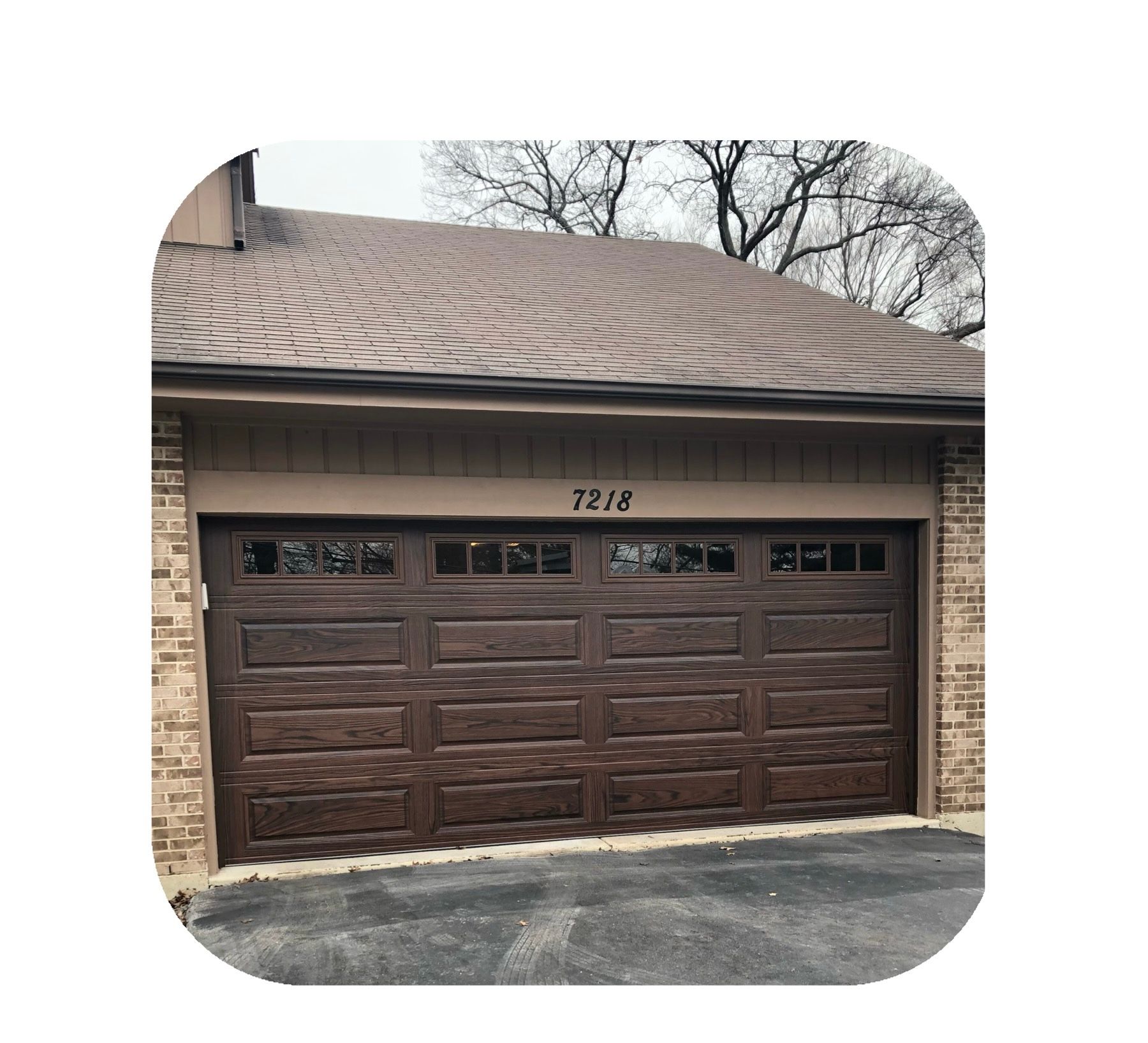 Brown garage door with windows, tan trim, and brick siding; the number 