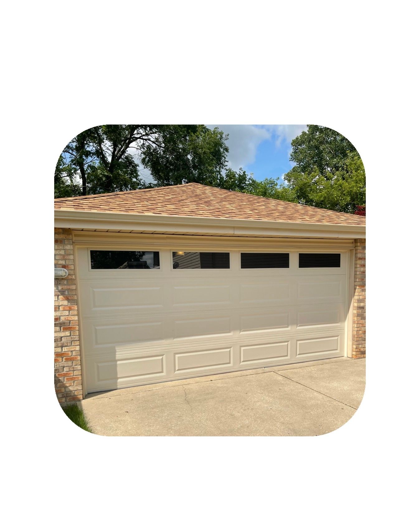 Beige garage door with small windows, tan roof, and brick side.