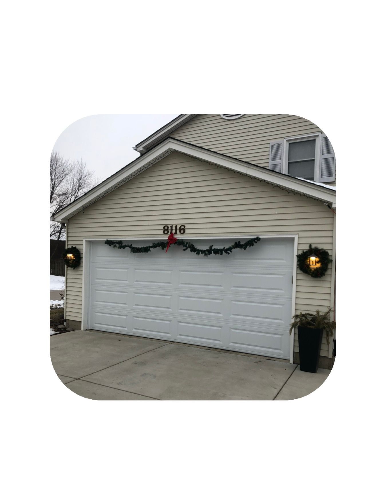 Garage with Christmas decorations: garland above the door, wreaths on sides, and the number 806.