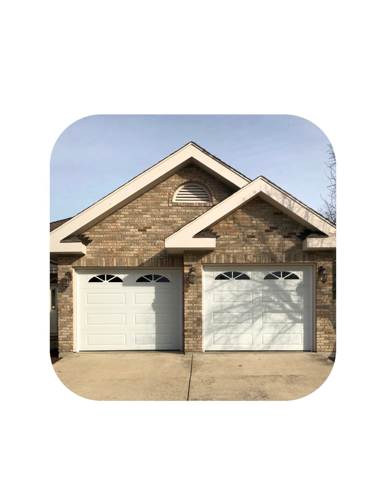 Two-car garage with white doors, brick facade, and a light blue sky.