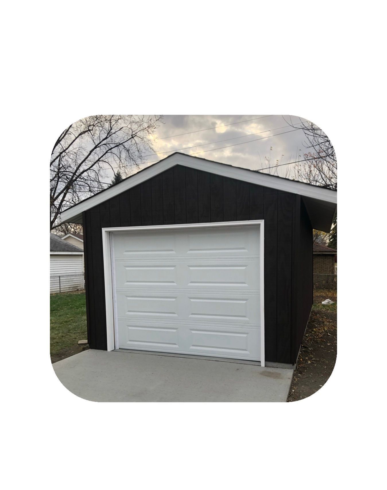 Black garage with a white door and a concrete driveway.