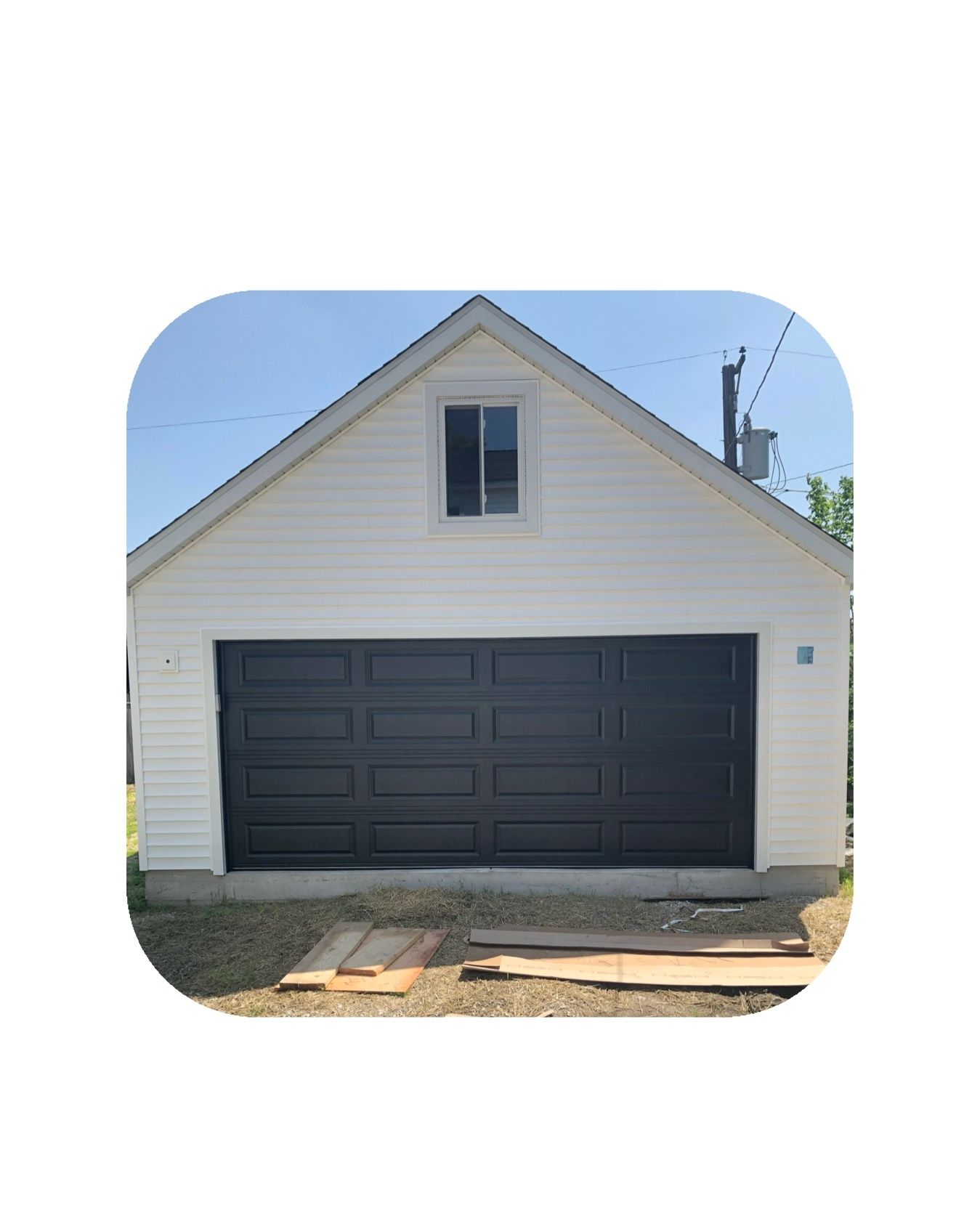 White garage with a gray garage door, small window, and clear blue sky.
