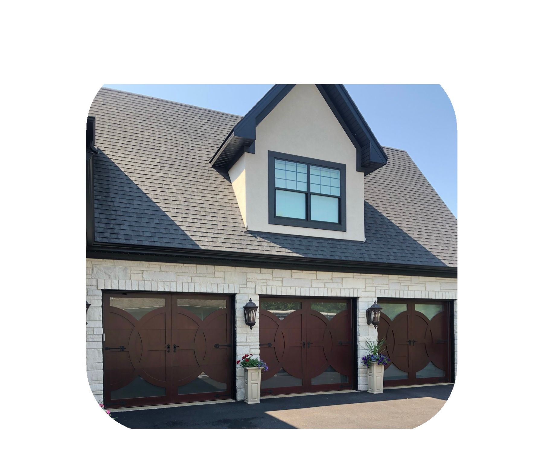 Three-car garage with dark brown doors, stone facade, and a dormer window.