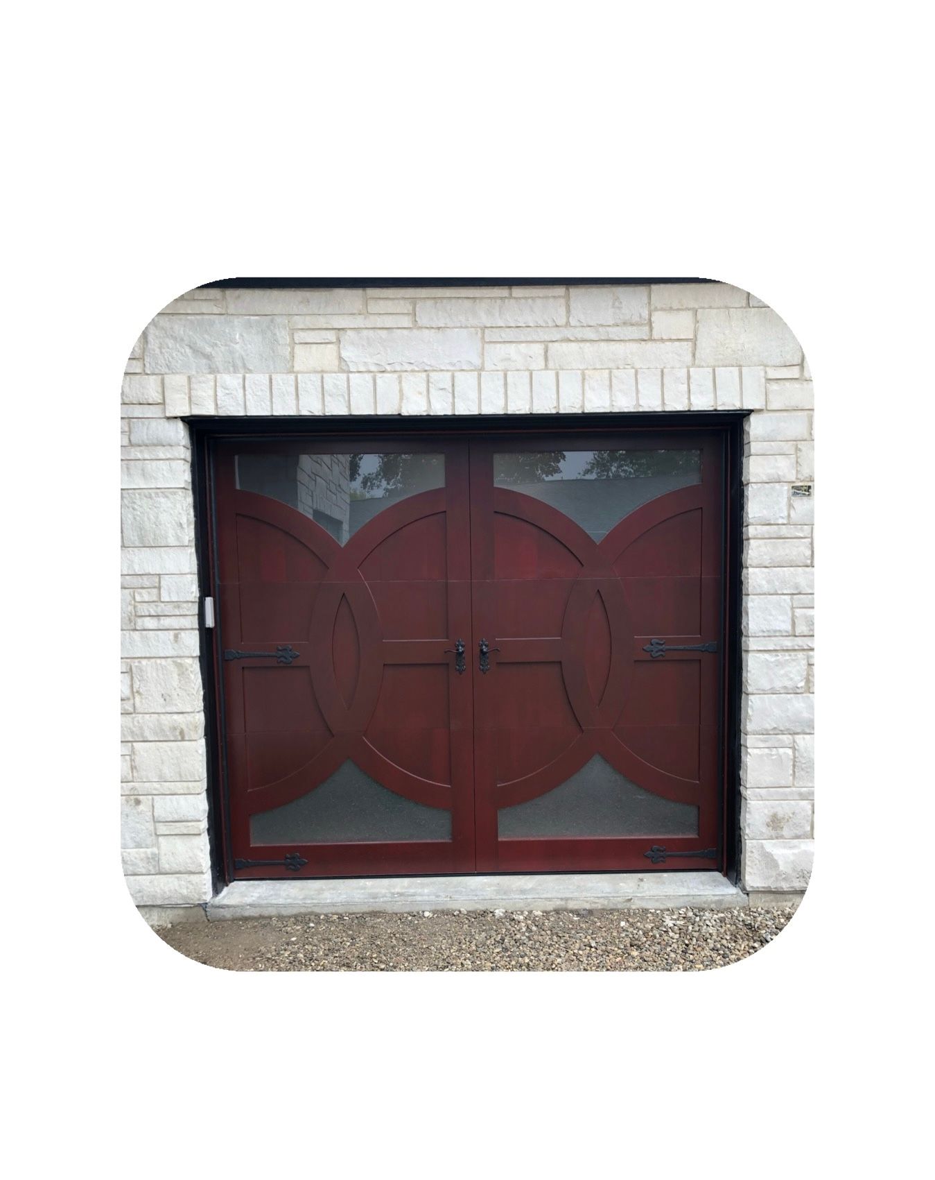 Red double garage door with circular design, set in a stone surround.