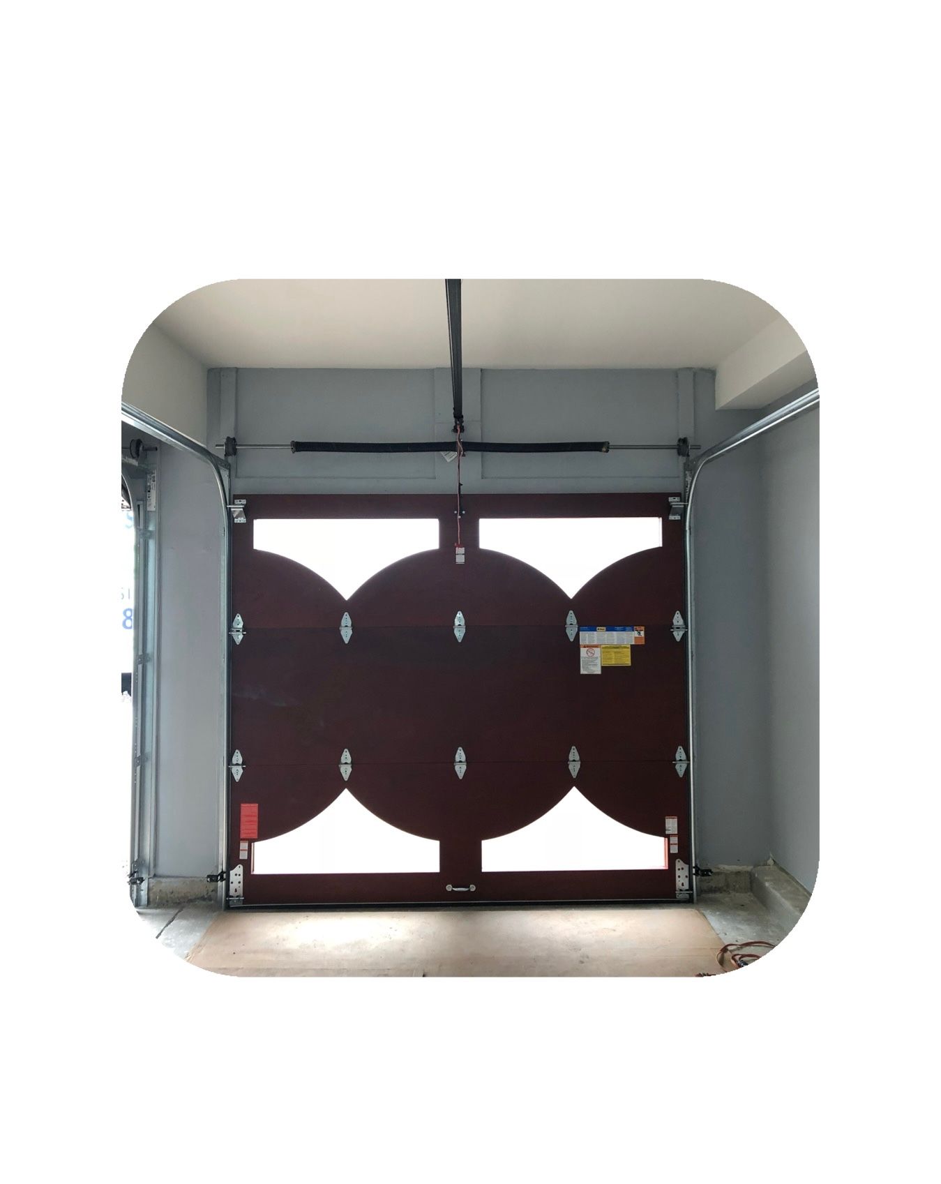 Dark brown garage door with circular window panels, inside a garage.