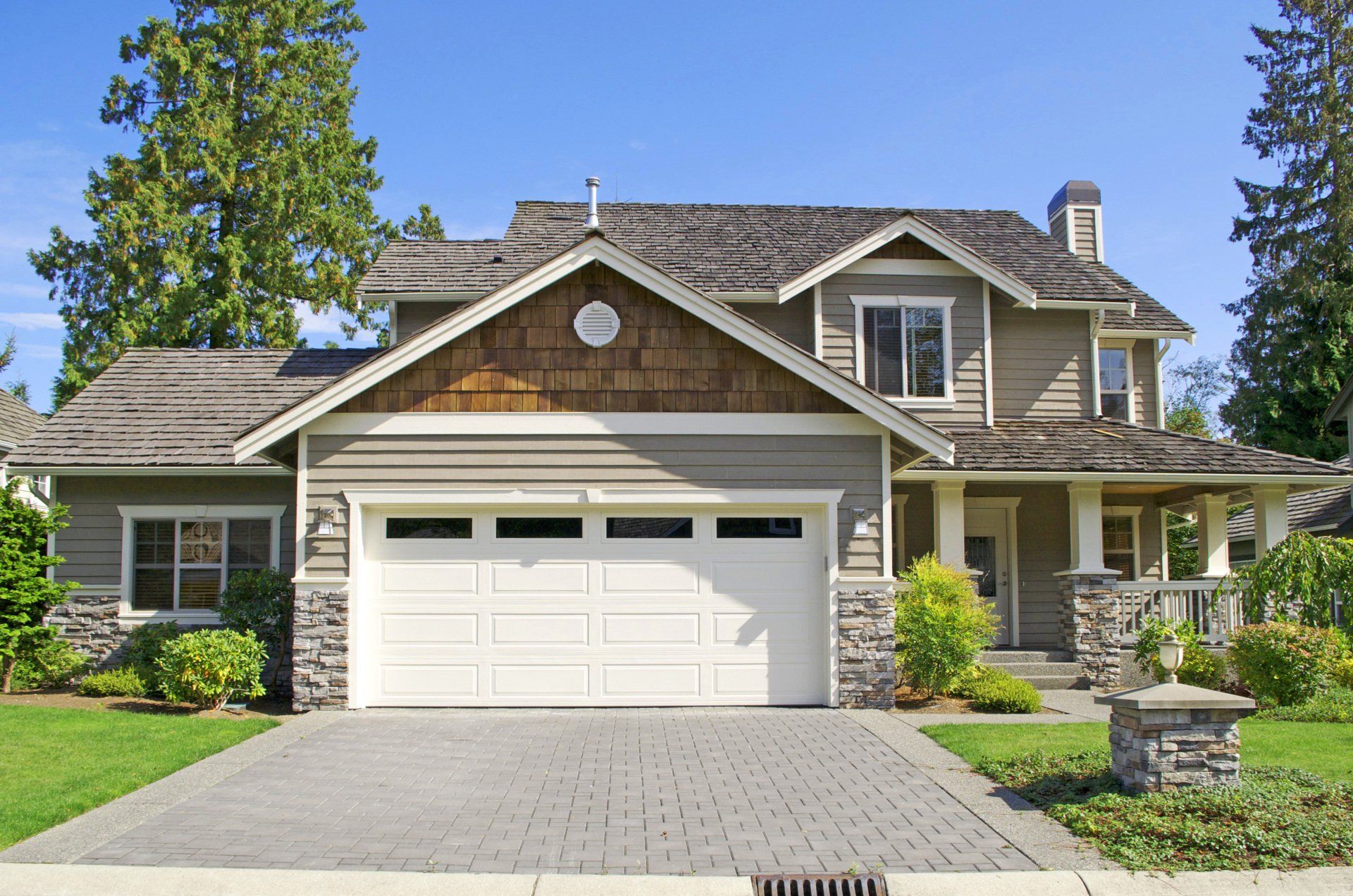Modern style home boasts two car garage framed by blue siding and natural stone wall trim.