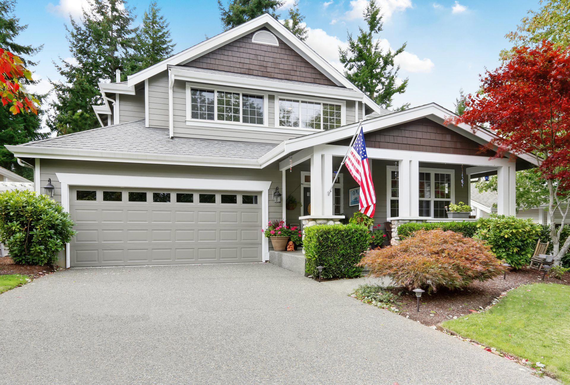 Nice curb appeal of grey house with garage and driveway.