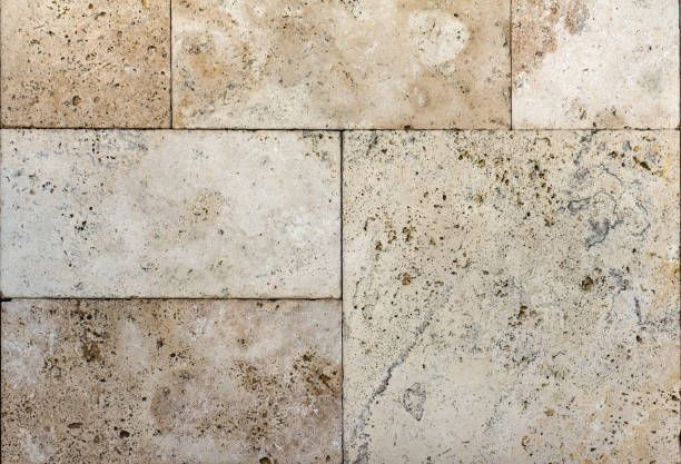 Close-up of beige travertine stone tiles with natural textured surface.